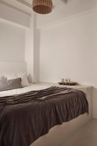 a white bedroom with a bed with a black blanket at Maison Central in Mikonos