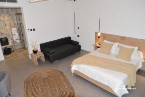 a bedroom with a large bed and a black couch at Nisaki Hotel & Elite Suites in Ermoupoli