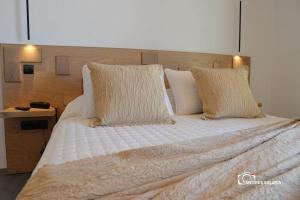 a large bed with white sheets and pillows at Nisaki Hotel & Elite Suites in Ermoupoli