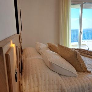 1 dormitorio con cama con almohadas y ventana en Nisaki Hotel & Elite Suites, en Ermoupoli