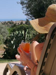una mujer sentada en una silla sosteniendo una bebida en Villa La Lumia B&B Suites & Apartments en Agrigento
