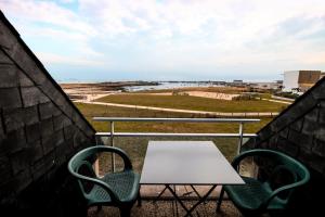 een tafel en stoelen op een balkon met uitzicht op de oceaan bij APPART-DUPLEX VUE MER PANORAMIQUE BALCON & PISCINE proche commerce in Penmarcʼh