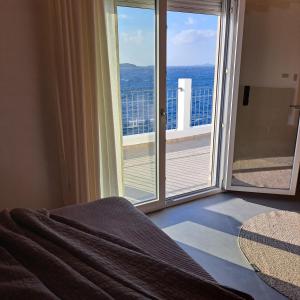 a bedroom with a view of the ocean from a balcony at Nisaki Hotel & Elite Suites in Ermoupoli