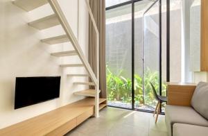 a living room with a staircase and a tv at Sakura Terrace Benhil in Jakarta