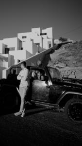 a man is standing next to a car at CUBIC Mykonos Seafront Design Suites in Ornos