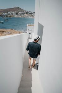 un hombre caminando por las escaleras de un edificio blanco en CUBIC Mykonos Seafront Design Suites en Ornos