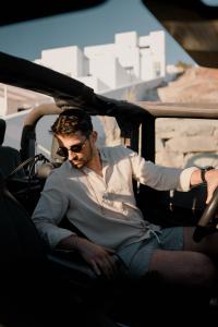 un hombre sentado en el asiento trasero de un coche en CUBIC Mykonos Seafront Design Suites en Ornos
