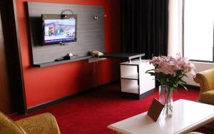 a living room with a tv on a red wall at Grand Riverview Hotel in Kota Bharu