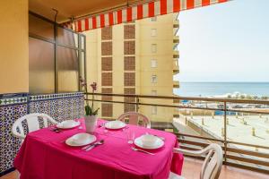 een tafel met een roze tafelkleed op een balkon met uitzicht op de oceaan bij Ubicación magnífica, zona tranquila in Fuengirola