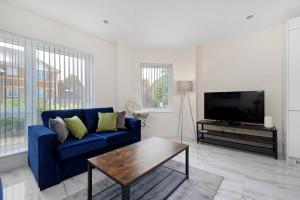 ein Wohnzimmer mit einem blauen Sofa und einem TV in der Unterkunft Oxford Rd 2 Bed Serviced Apartment 06 with Parking, Reading By 360Stays in Reading