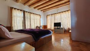 a bedroom with a bed and a tv and windows at Serdung Guest House in Leh