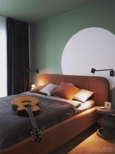 a bedroom with a guitar on a bed with a lamp at Piękny Apartament nad Odrą w centrum Wrocławia in Wrocław