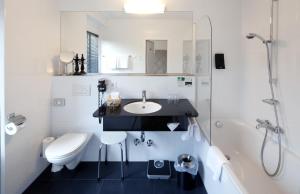 a bathroom with a sink and a toilet and a shower at Hotel Weißes Kreuz in Bregenz +18 photos