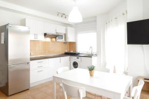 a kitchen with white cabinets and a white table at Casa Nadia in Corralejo