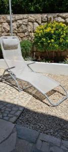 a white chair sitting on the ground under an umbrella at Apartments Dora in Pag