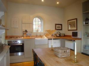 cocina con armarios blancos y mesa de madera en The Engine House, en East Dereham