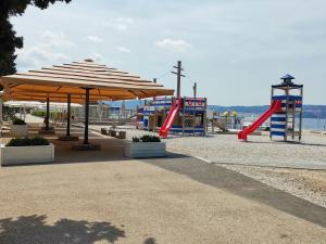 a playground with a slide and an umbrella at APARTMA VATOVEC in Ankaran