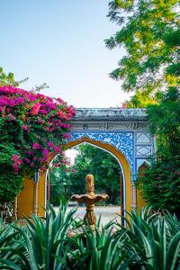 Diggi Palace - A City Center Hidden Heritage Gem في جايبور: ممر مع تمثال تحت جسر مع الزهور