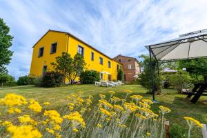una casa gialla con fiori gialli nel cortile di L'Olmo di Casigliano a Cessapalombo