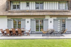 a patio with a table and chairs in front of a house at Luxueuse Chaumière 4 Chambres avec jardin in Deauville