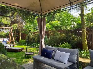 a couch sitting under a gazebo in a garden at Prowansja 2 - rodzinny domek letniskowy z prywatnym ogródkiem in Stegna