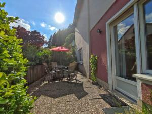 un patio con mesa, sillas y sombrilla en Ferienwohnung Eschenberg en Winterberg