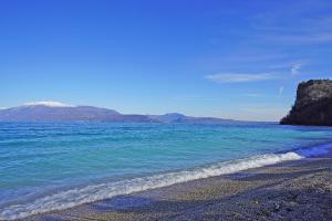 una playa con agua azul y montañas de fondo en Villa Giulia en Manerba del Garda