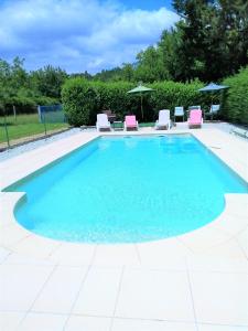 a swimming pool with blue water and pink chairs at Le Grand Chemin de La Vie in Montcaret