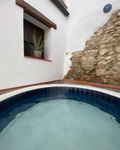una piscina frente a una casa con una pared de piedra en Tío Genaro, en Cumbres de San Bartolomé