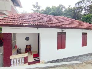 a small white house with a red roof at Olivia Homestay Idukki in Idukki