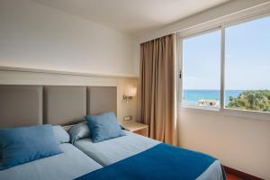 a hotel room with a bed and a large window at Hotel Ivory Playa Sports & Spa in Port d'Alcudia