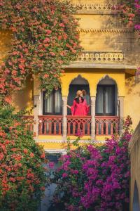 una persona seduta su un balcone con fiori di Diggi Palace - A City Center Hidden Heritage Gem a Jaipur