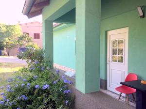 梅杜林Double room with bathroom, WiFi, airco, parking, washing machine, grill的绿色的房子,有白色的门和紫色的鲜花