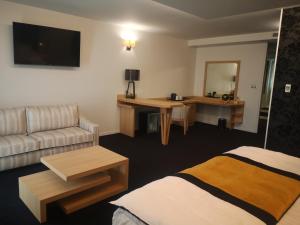 een hotelkamer met een bed en een bank bij Les Suites - Konine 4 - Hotel & Bar & Restaurant in Montceau-les-Mines