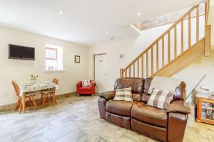 a living room with a leather couch and a table at Jenny's Cottage in Oldham