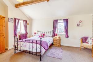 a bedroom with a bed and a chair and windows at Jenny's Cottage in Oldham