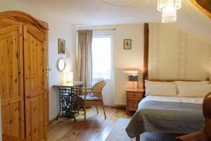 a bedroom with a bed and a desk and a window at Guest House Wiejska Sielanka in Brody