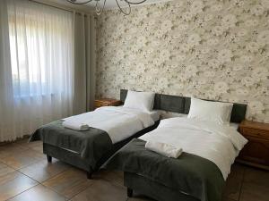 um quarto com duas camas e uma parede com flores em Apartamenty Jaskinia Solna em Ruda Śląska
