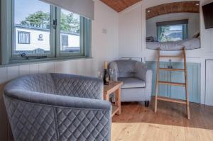 een woonkamer met 2 stoelen en een stapelbed bij Willow - 1 Bedroom Shepherds Hut - Amroth in Amroth