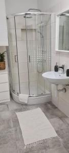 een witte badkamer met een douche en een wastafel bij Apartments Dora in Pag