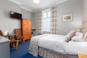a bedroom with a bed and a desk and a chair at Ormsgill Inn in Barrow in Furness
