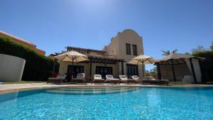 a pool with chairs and umbrellas next to a house at Private Villa Heated Pool & Enclosed Garden in Hurghada +35 photos