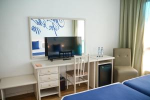 a bedroom with a desk with a television and a bed at BPM Lloret Hotel in Lloret de Mar