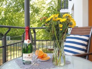 eine Flasche Champagner und eine Vase Blumen auf dem Tisch in der Unterkunft Kaiservillen Heringsdorf - 1-Raum-Ferienwohnung mit Balkon D113 in Heringsdorf