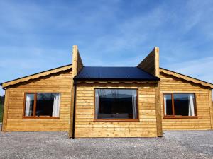 a wooden house with a black roof and two windows at Dulrush Fishing Lodge and Guest House in Belleek