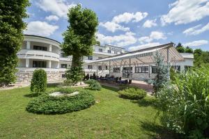 a large white building with a garden in front of it at Hotel Korona in Harkány