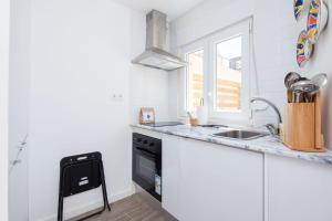 a white kitchen with a sink and a stove at Designer Flats in Lapa by LovelyStay in Lisbon