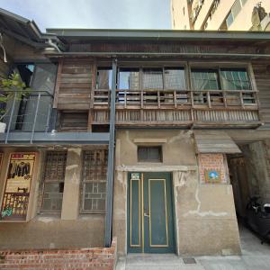 un vecchio edificio con porta verde e balcone di Jerry's Mazehut Hostel a Tainan