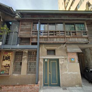 an old building with a green door and a balcony at Jerry's Mazehut Hostel in Tainan