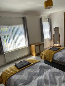 a bedroom with two beds and a mirror and windows at 4-6 Guests in centre location with stunning views in Llanberis